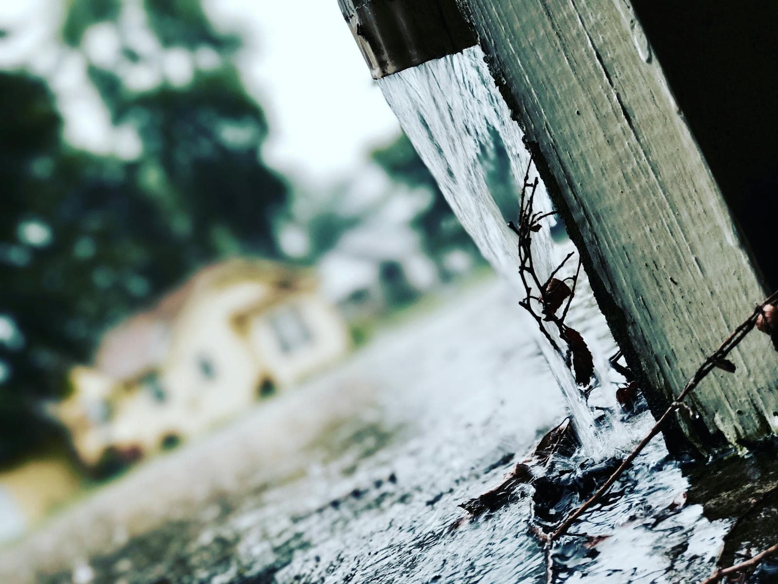 Rainwater flowing from a gutter during heavy rain.
