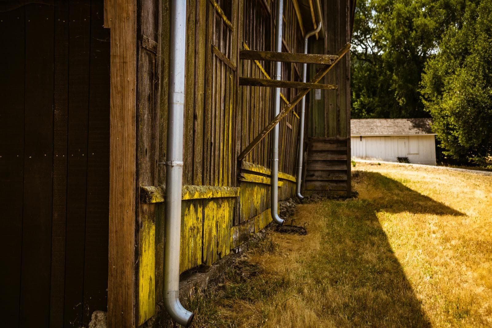 Exterior gutter and downspout sections along a weathered building.